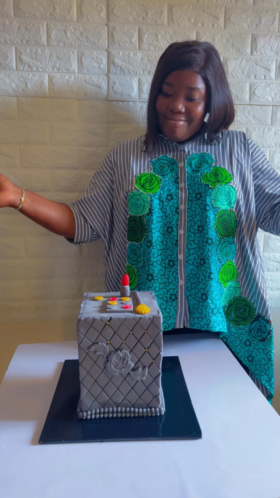 Owner of TTS Cakes applying makeup to a decorative cake